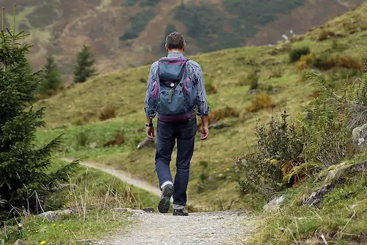 Man hiking in grassy hills wearing a backpack
